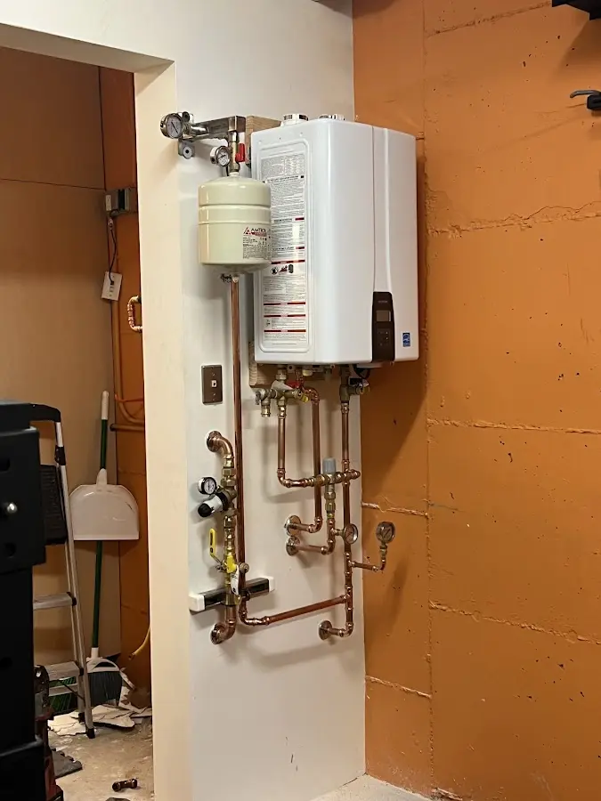Plumbing technician inspecting water heater connections in Coloma
